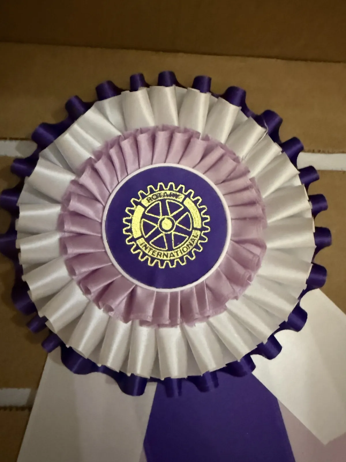 Close-up of a lavender and white layered rosette with a gold printed center